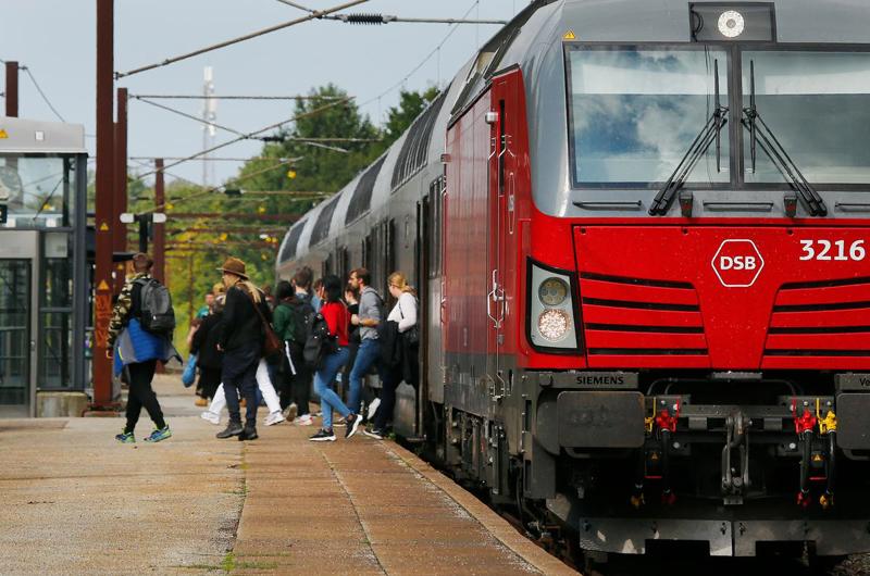 Passagerer stiger af et tog på en perron. Forrest er et Vectron-lokomotiv tydeligt.