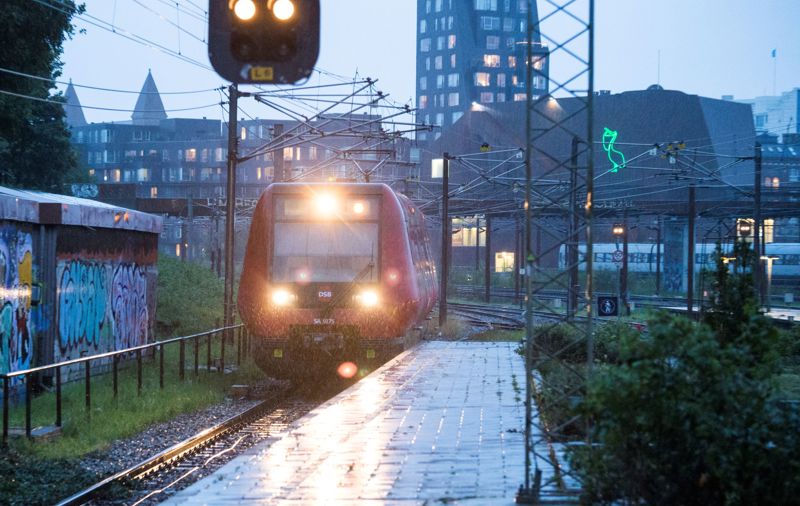 Et S-tog kører til en station i regnvejr