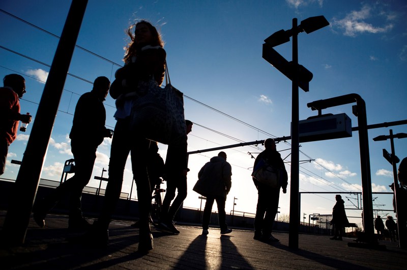 Passagerer på togperron fotograferet i modlys