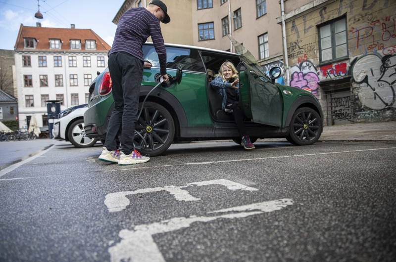 Mand oplader en elbil på en p-plads i København, der er reserveret til elbiler.