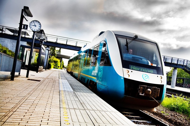 Et Arriva-tog i retning mod Herning holder ved en station