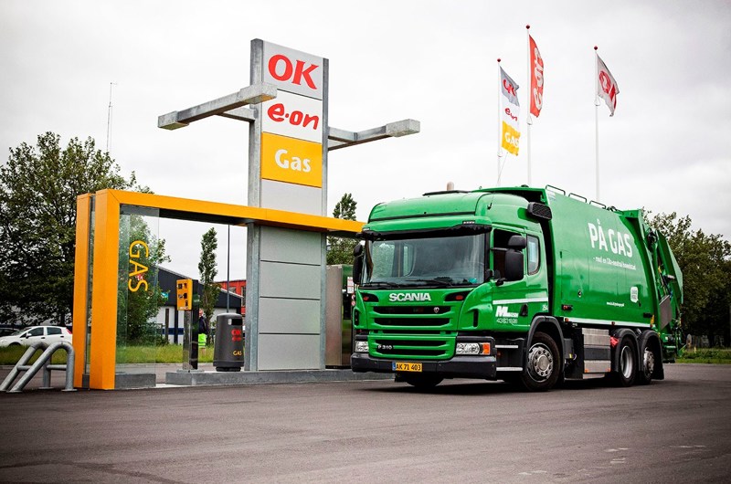 Gasdrevet skraldebil tanker ved en tankstation.