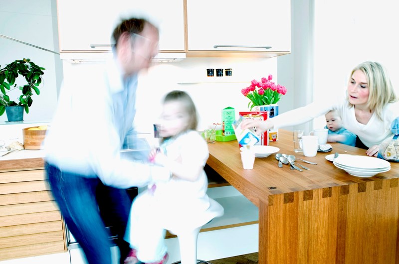 En familie med to forældre og to børn ved morgenbordet